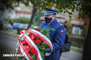 Komendant Wojewódzki Policji trzymający wiązankę kwiatów.
