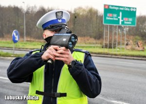 Policjant ruchu drogowego wykorzystujący miernik do mierzenia prędkości