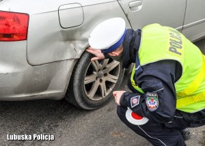 Policjant ruchu drogowego sprawdza opony kontrolowanego auta