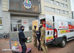 policjanci pakują do busa zebrane przedmioty