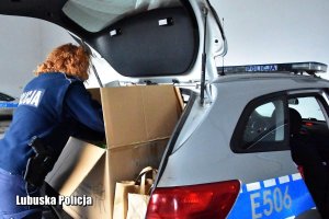 Policjantka pakuje do bagażnika radiowozu paczkę dla potrzebujących