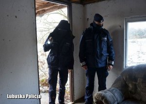 Policjanci sprawdzają wnętrze opuszczonego budynku.