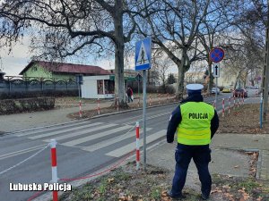 policjant obserwuje ruch pojazdów w rejonie przejścia dla pieszych