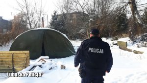 Policjant sprawdza czy osoby bezdomne wymagający pomocy przebywają w zaśnieżonym terenie