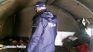 Policjant sprawdza czy w namiocie nie przebywają bezdomni wymagający pomocy