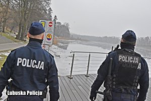 Umundurowani policjanci sprawdzają zamarznięte jezioro.