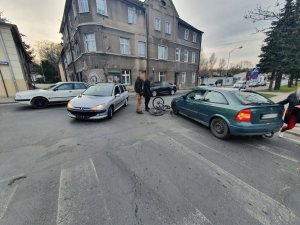 Dwa samochody, a pomiędzy nimi uszkodzony w wyniku kolizji rower