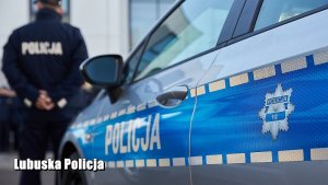 Policyjny radiowóz oznakowany. W  tle policjanci