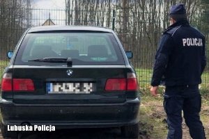 policjant stoi przy czarnym BMW