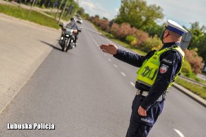Umundurowany policjant zatrzymuje motocyklistę do kontroli drogowej.
