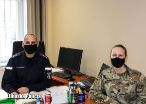 Policjant siedzący za biurkiem, a obok żołnierz armii amerykańskiej.