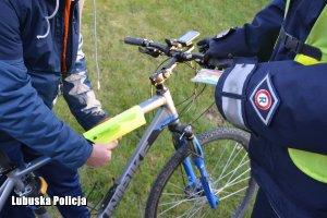 policjant wręczył odblask rowerzyście, który zakłada go na rower