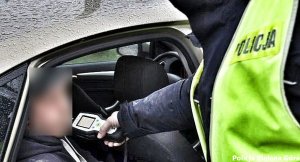 Policjant przeprowadza badanie na zawartość alkoholu w wydychanym powietrzu na kierowcy