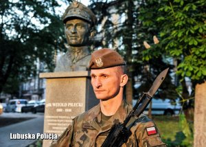 Żołnierz, a w tle pomnik Rotmistrza Witolda Pileckiego.
