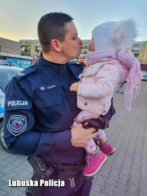 Policjant z dzieckiem na rękach.