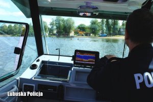 Policjant na łodzi patroluje nadbrzeże, gdzie kapią się ludzie