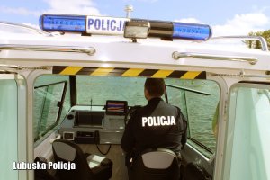 Policjant na łodzi patroluje nadbrzeże, gdzie kapią się ludzie