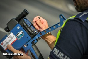 policjant reguluje urządzenie do pomiaru prędkości