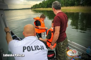 policjant rozmawia z osobami na łodzi