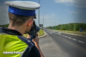 Policjant ruchu drogowego kontroluje prędkość z jaką porusza się pojazd na drodze.