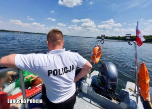 Policjant w trakcie czynności legitymowania osób na łodzi.