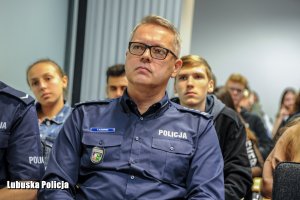 Zastępca Komendanta Wojewódzkiego Policji w Gorzowie Wielkopolskim siedzi wraz z innymi uczestnikami debaty na sali konferencyjnej