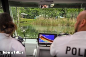 Policjantka i policjant na łodzi patrolują jezioro