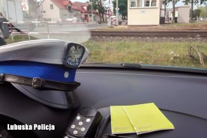 policyjna czapka w radiowozie i przejazd kolejowy w tle