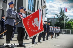 sztandar i nowi policjanci stoją na baczność