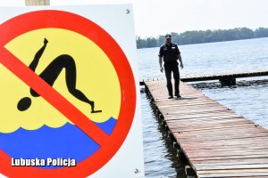Na moście policjant. Widok na znak informujący o zakazie skoków do wody
