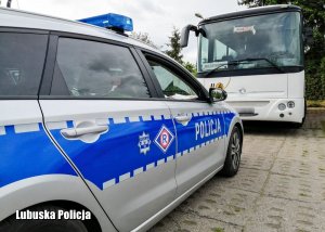 Policyjny radiowóz przed autobusem.