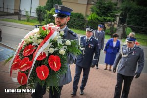 policjant niesie kwiaty a za nim kadra kierownicza Lubuskiej Policji
