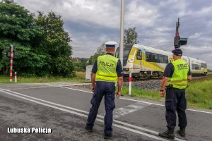 policjanci stoją przed przejazdem kolejowym