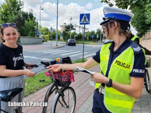 Policjantka wręcza odblask kierującej rowerem