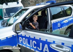 Chłopiec za kierownicą policyjnego radiowozu.