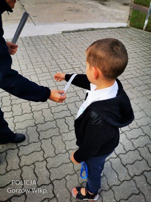 Mały chłopiec otrzymuje element odblaskowy na rękę.