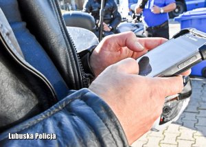 Policjant drogówki trzyma smartfona.