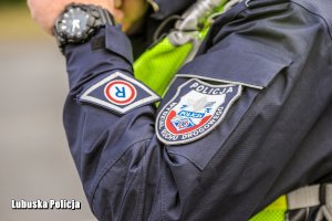 Ramię policjanta z naszywką na kurtce - napis: Policja Wydział Ruchu Drogowego.