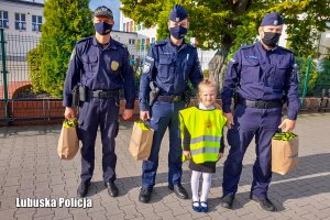 Policjanci i strażnik miejski stojący z dziewczynką.