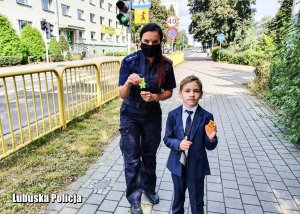 Policjantka z chłopcem pokazująca elementy odblaskowe.