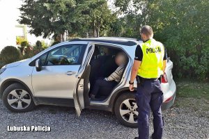 policjant stoi przy samochodzie, w którym siedzi kobieta