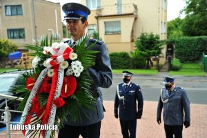 Policjant z posterunku honorowego składa wieniec. W tle kierownictwo Lubuskiej Policji