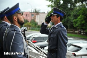 Salutujący policjant, obok policjanci z posterunku honorowego