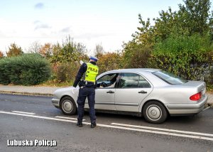 Policjant drogówki wskazuje kierowcy kierunek jazdy.