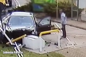 Rozbity pojazd osobowy na terenie stacji benzynowej, a obok pojazdu stojący mężczyzna.