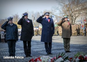 Przedstawiciele służb mundurowych oddają honor przed pomnikiem.