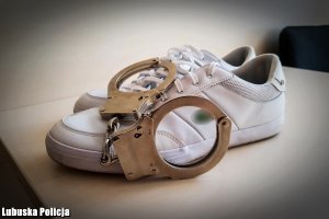 Metalowe kajdanki na białych butach.