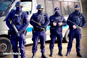 czterech policjantów Samodzielnego Pododdziału Prewencji Policji z długą bronią na tle radiowozu