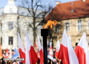 Palący się płomień, na tle flag Polski.