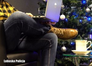 Mężczyzna siedzi na fotelu z komputerem. W tle choinka bożonarodzeniowa.
